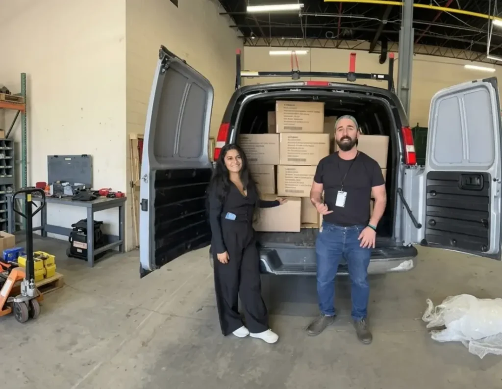 The team at the van in the warehouse, loaded with boxes
